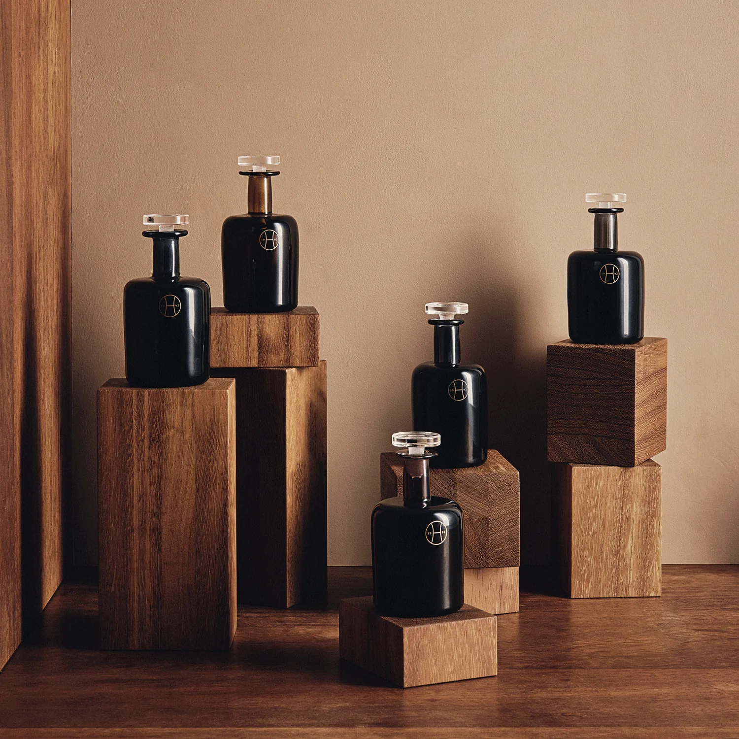 Perfumer H 深色玻璃香氛瓶陳列於木質展示座